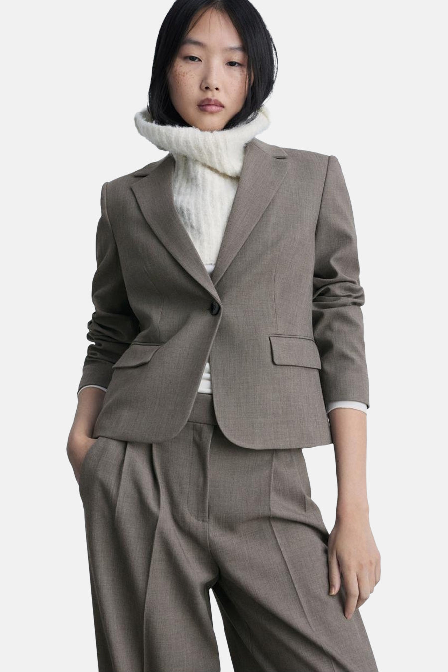 Bruine kostuumbroek van MANGO, gedragen met een bijpassende blazer en een witte coltrui.