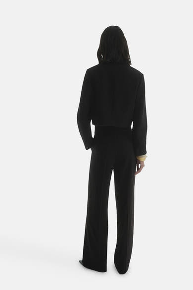 Zwarte korte blazer van MANGO, gedragen met een bijpassende zwarte pantalon, achterzicht.