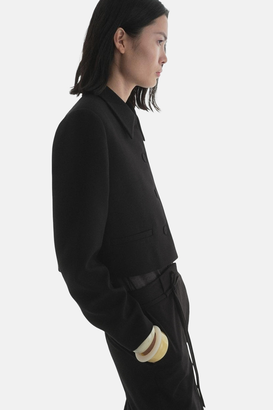 Zwarte blazer van MANGO, korte pasvorm met lange mouwen, gedragen met een bijpassende zwarte broek.