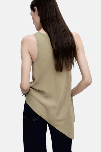 Blouse kaki sans manches de MANGO, portée avec un jean bleu foncé.