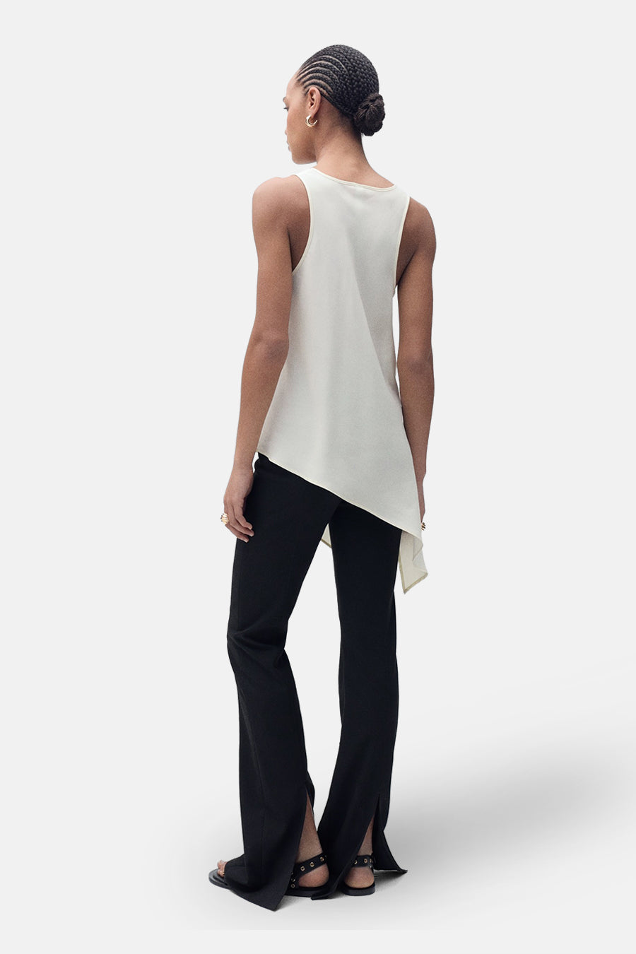 Ecru mouwloos blouse van MANGO, asymmetrisch, gedragen met een zwarte wijde broek en sandalen.