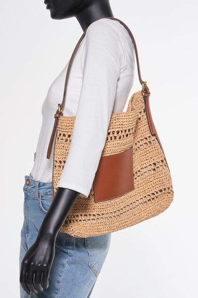 Sac à bandoulière en paille brun de MANGO, avec poche plaquée en cuir, porté sur un t-shirt blanc et un jean.