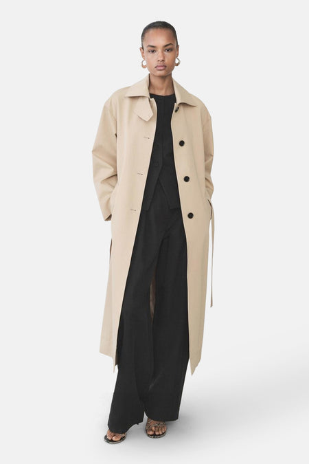 Zwarte broek van MANGO, losse pasvorm en wijde pijpen, gedragen met een beige, geknoopte jas.