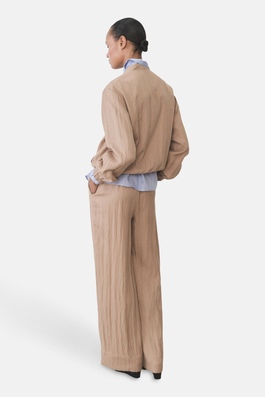 Veste courte brune de MANGO, portée sur une chemise bleue, avec un pantalon assorti.