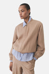 Veste courte marron de MANGO, portée sur une chemise bleu clair à rayures.