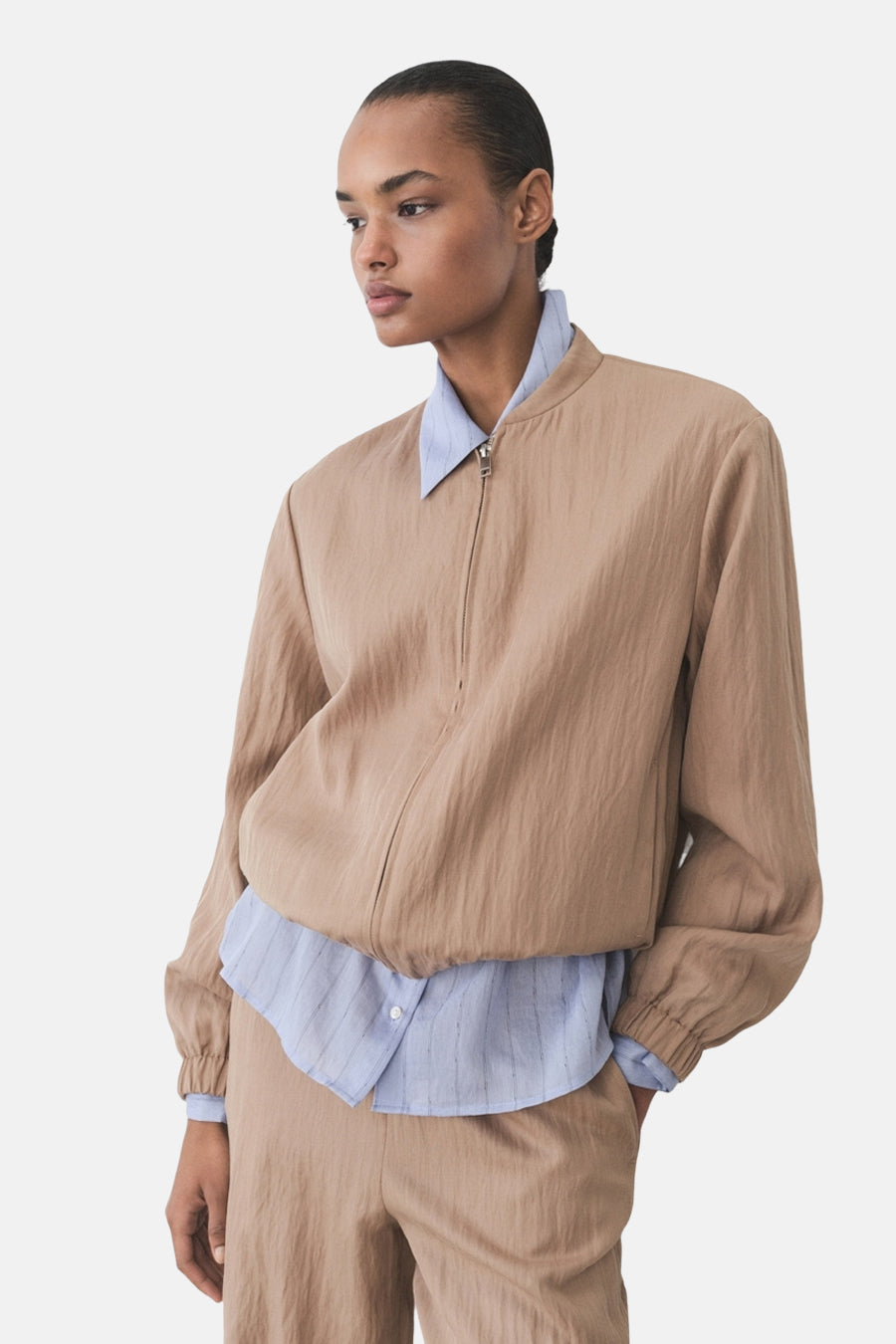Veste courte marron de MANGO, portée sur une chemise bleu clair à rayures.
