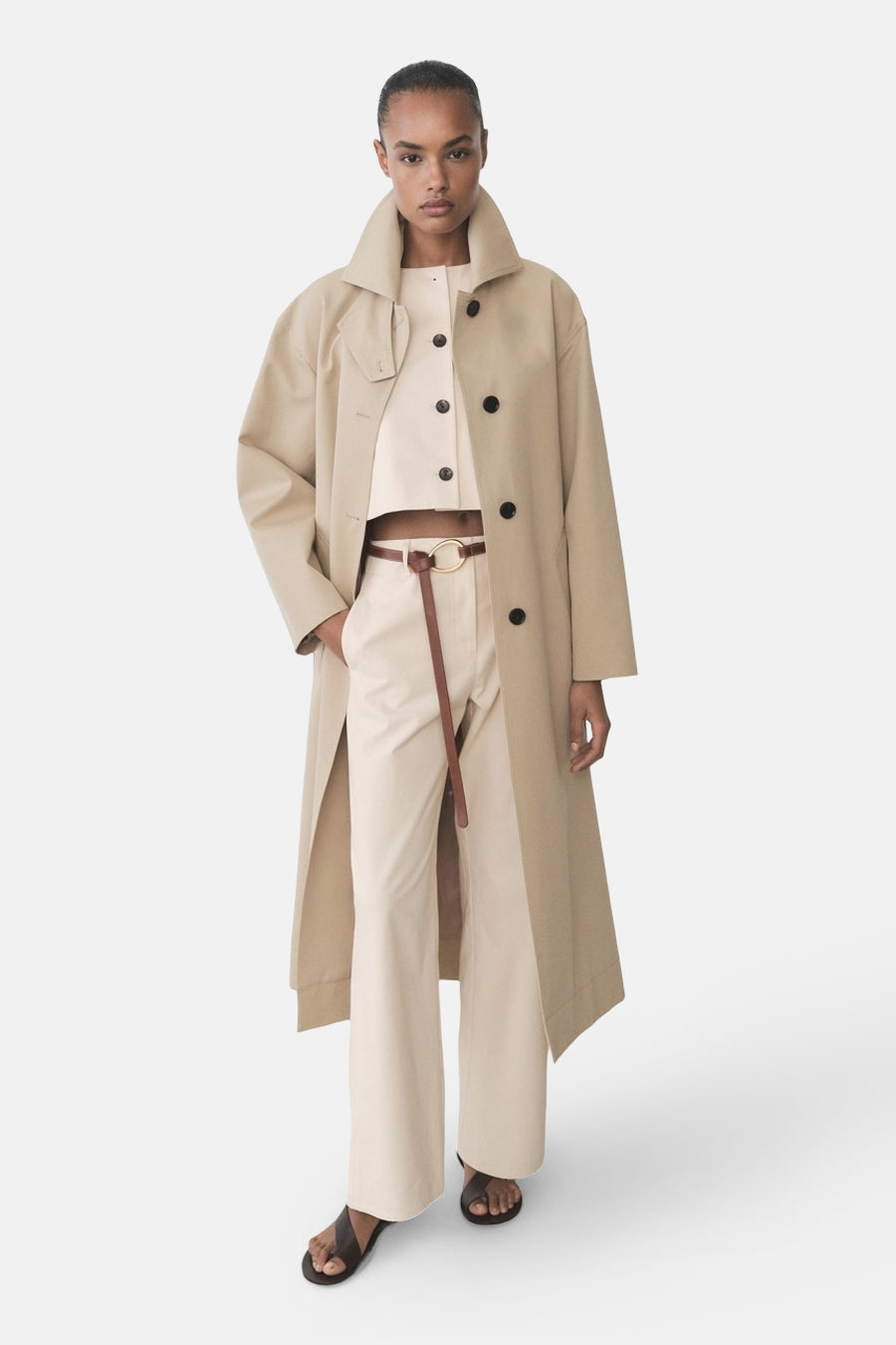 Blazer écru de MANGO porté avec un pantalon taille haute, une ceinture en cuir et des sandales plates.

