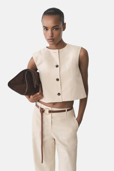 Blazer écru de MANGO avec trois boutons, porté avec un pantalon taille haute et une ceinture en cuir.