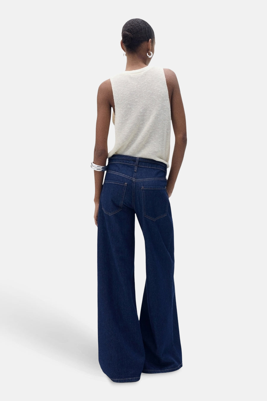 Débardeur écru de MANGO, porté avec un jean ample bleu marine, et des accessoires argentés.