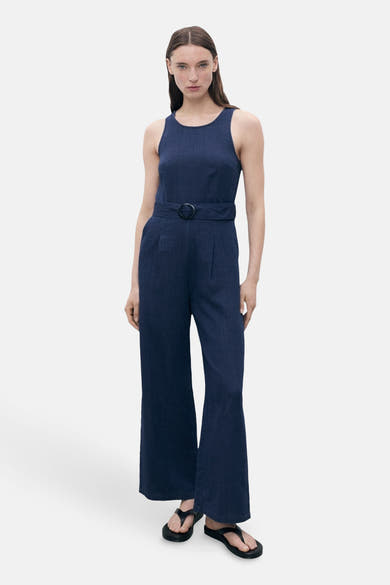 Combinaison bleu marine de MANGO, avec ceinture à boucle et jambes évasées, portée avec des sandales noires.