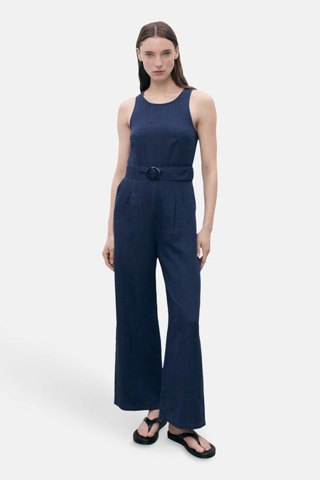 Combinaison bleu marine de MANGO, avec ceinture à boucle et jambes évasées, portée avec des sandales noires.