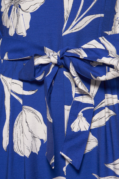 Combinaison bleue à fleurs de MANGO, ornée d'une ceinture nouée et d'un motif floral blanc.
