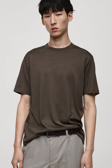 Kaki T-shirt met korte mouwen van MANGO, gedragen met een lichtgrijze broek, achtergezicht.