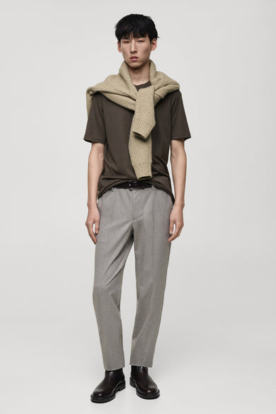 Kaki T-shirt met korte mouwen van MANGO, met een beige gebreide trui geknoopt over de schouders.