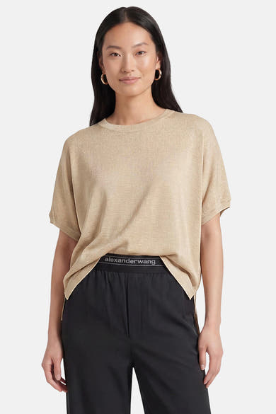 Golden short-sleeve knit t-shirt by Alexander Wang, relaxed fit with round neckline, worn with black pants and gold hoop earrings.