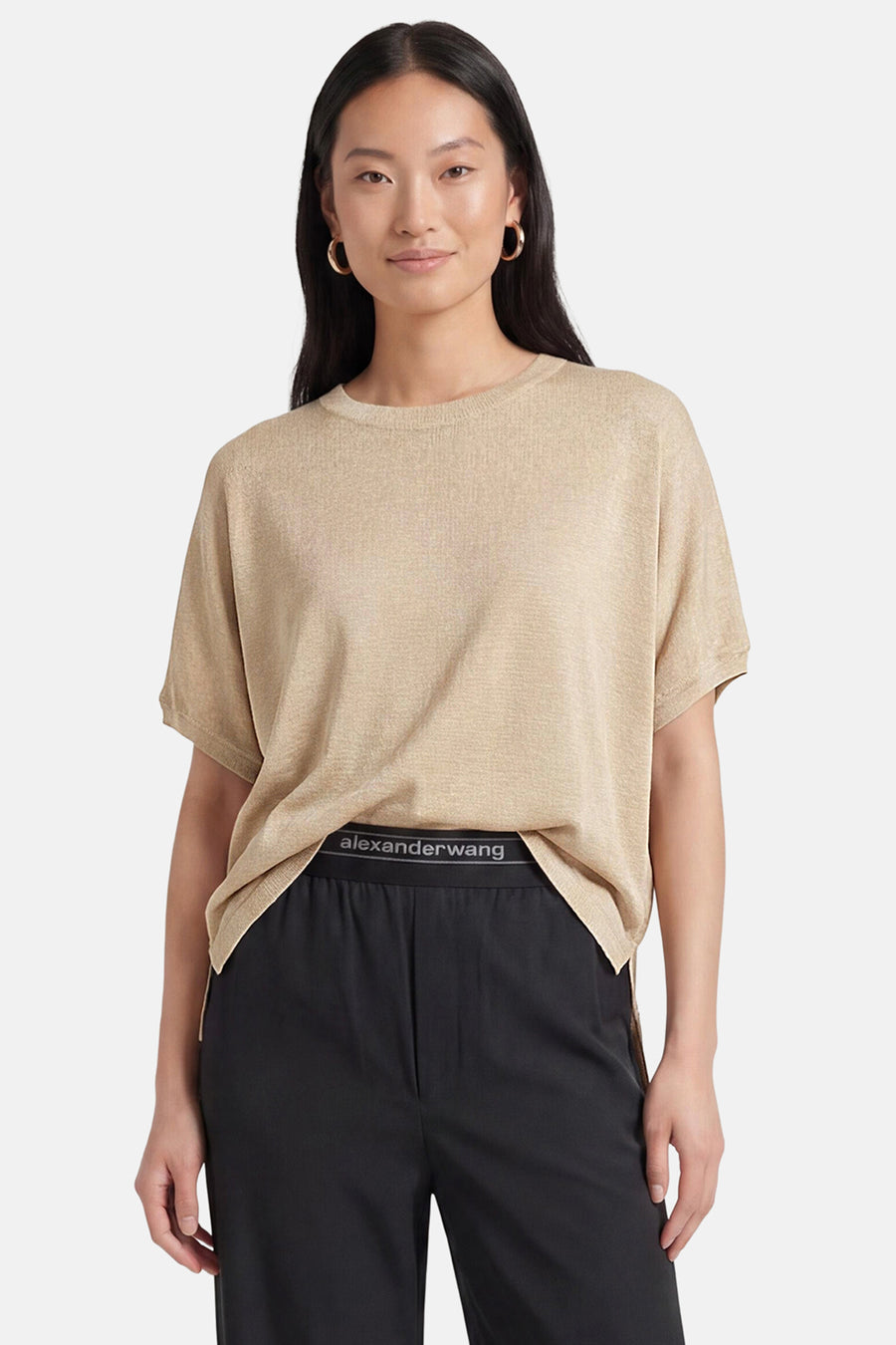 Golden short-sleeve knit t-shirt by Alexander Wang, relaxed fit with round neckline, worn with black pants and gold hoop earrings.