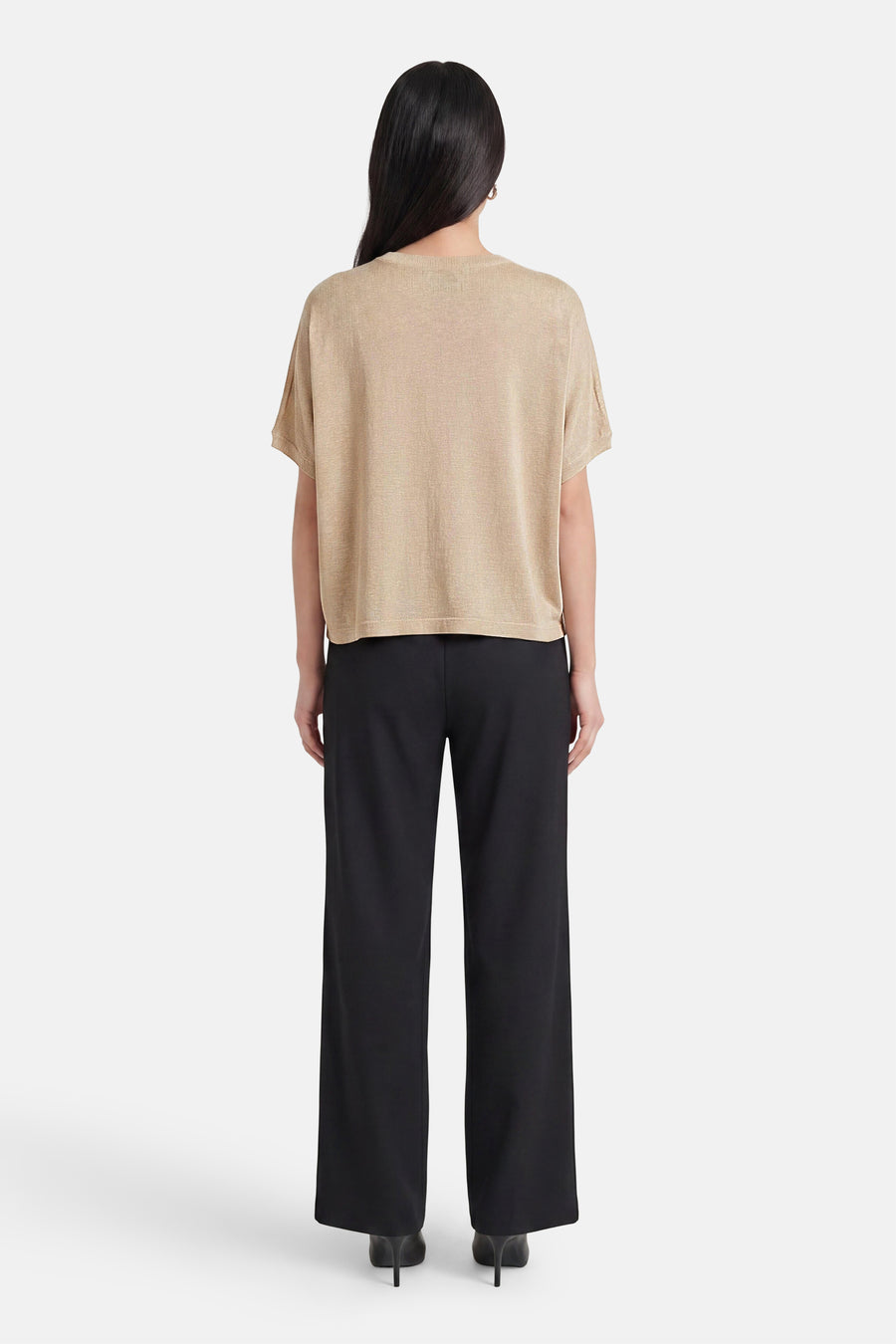 Golden short-sleeve T-shirt with relaxed fit and ribbed neckline, back view on model wearing black wide-leg trousers and heels.