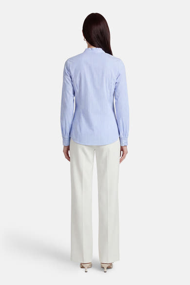 Chemise à manches longues bleue rayée de MORE & MORE, portée avec un pantalon blanc à jambes larges.