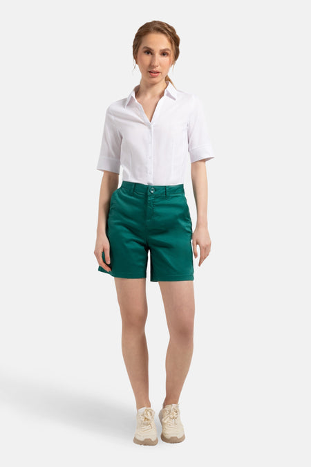 Chemisier blanc 3/4 de MORE & MORE, porté avec un short vert émeraude et des baskets couleur crème.