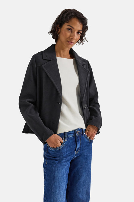 Kort blauw jasje van Street One, gedragen over een wit T-shirt en een blauwe jeans, handen in de zakken.