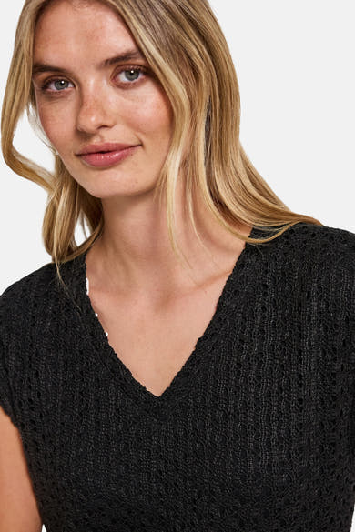 Zwarte jurk van STREEK EEN met opengebreide structuur, V-hals en delicate textuur.