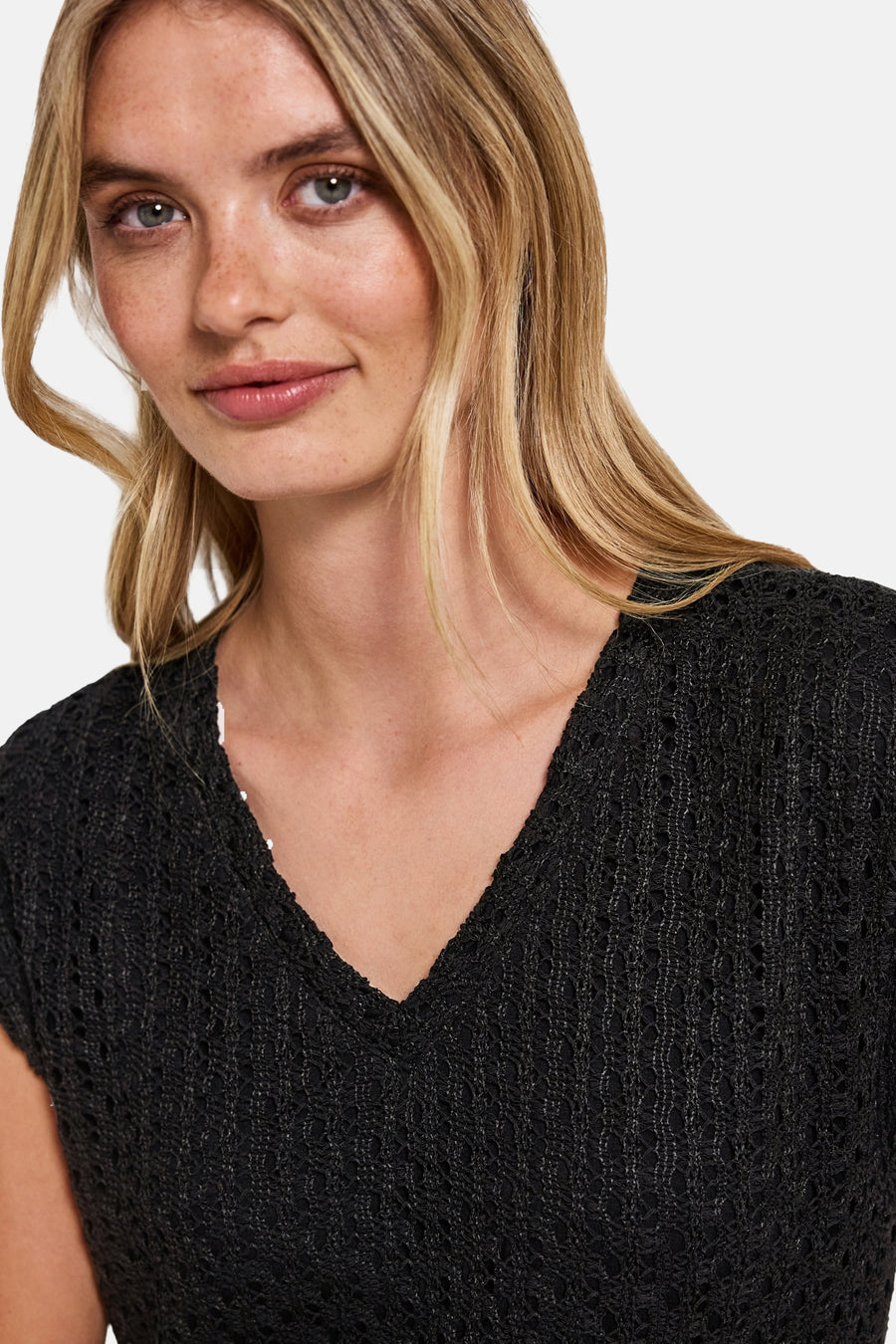 Zwarte jurk van STREEK EEN met opengebreide structuur, V-hals en delicate textuur.