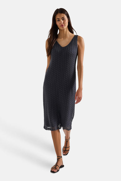 Blauwe jurk van STREET ONE, in een open gebreide stof met discreet patroon, gedragen met zwarte sandalen.
