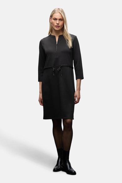 Zwarte jurk van STREET ONE met ritssluiting en trekkoord, gedragen met een zwarte panty.
