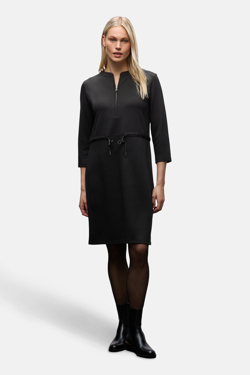 Zwarte jurk van STREET ONE met ritssluiting en trekkoord, gedragen met een zwarte panty.