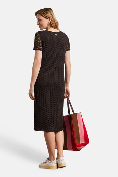 Robe midi brune de STREET ONE en maille ajourée, manches courtes et bouton argenté au dos, vue de dos. Le modèle tient un sac rayé et porte des baskets.
