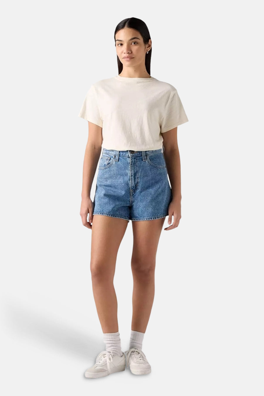 Short en denim par Levi's®, porté avec un t-shirt crème et des baskets blanches.