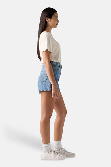 Short en denim délavé de Levi's®, porté avec un t-shirt blanc et des baskets blanches.