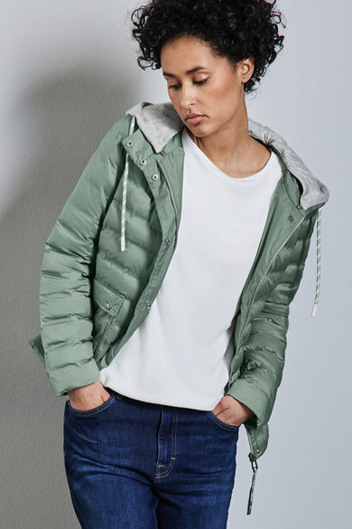 Korte groene jas van Street One, met grijze capuchon, gedragen met een wit T-shirt en een blauwe jeans.