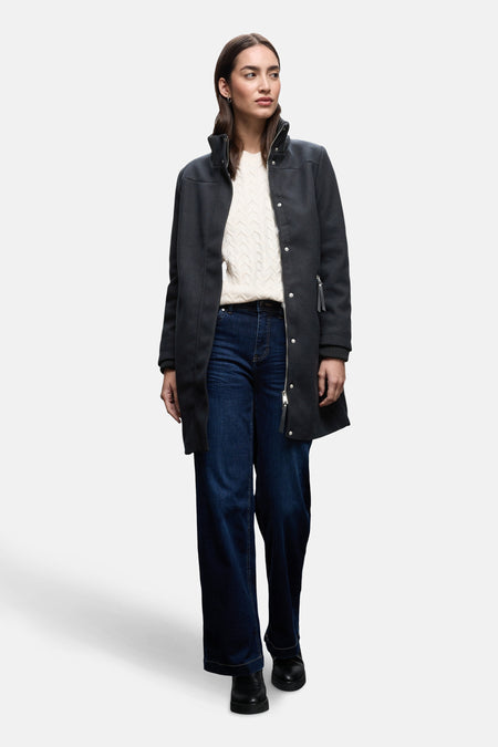 Lange blauwe jas van STREET ONE, met zilveren ritssluiting en gedragen met een witte kabeltrui.