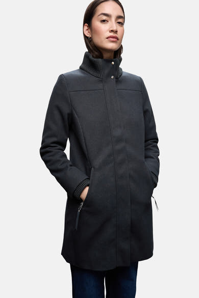 Lange blauwe jas van Street One, met opstaande kraag en ritszakken, gedragen met een spijkerbroek.