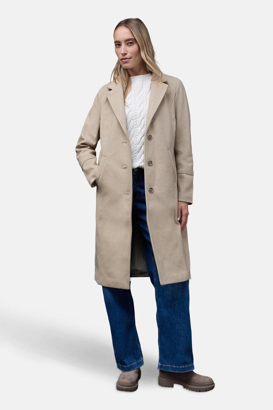Lange beige jas van Street One, met zakken, gedragen met een witte trui en een blauwe jeans.