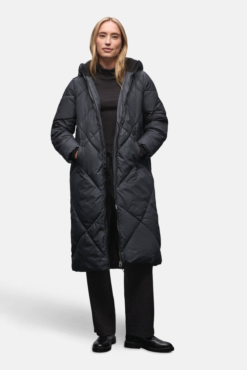 Veste longue bleue par STREET ONE, avec motif matelassé en losanges et capuche, portée avec un pantalon noir.
