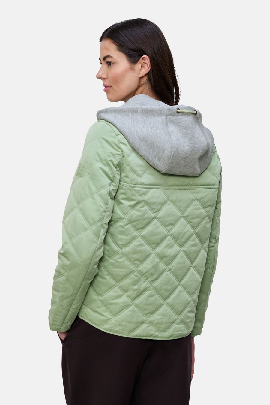 Veste courte vert clair matelassée de Street One avec capuche grise en sweat et pantalon marron.
