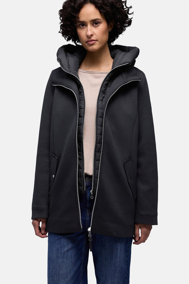 Korte blauwe jas van STREET ONE, gedragen met een sjaal met patroon, een beige trui, een spijkerbroek en een bruine tas.