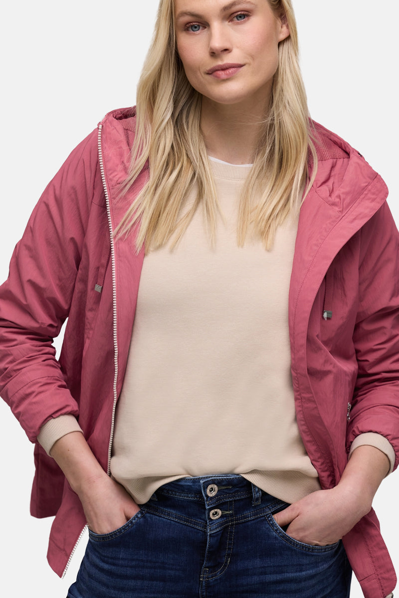 Korte roze jas van STREET ONE, gedragen met een wijde donkerblauwe jeans en zilveren sneakers, van opzij gezien.