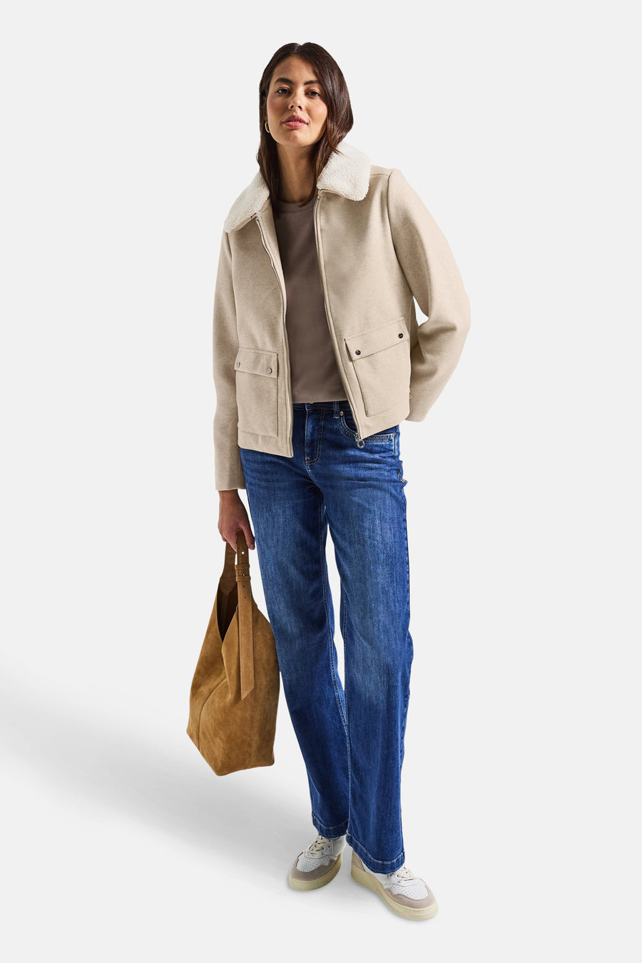 Veste courte beige par Street One avec col en fausse fourrure, portée avec un jean et un sac en cuir.