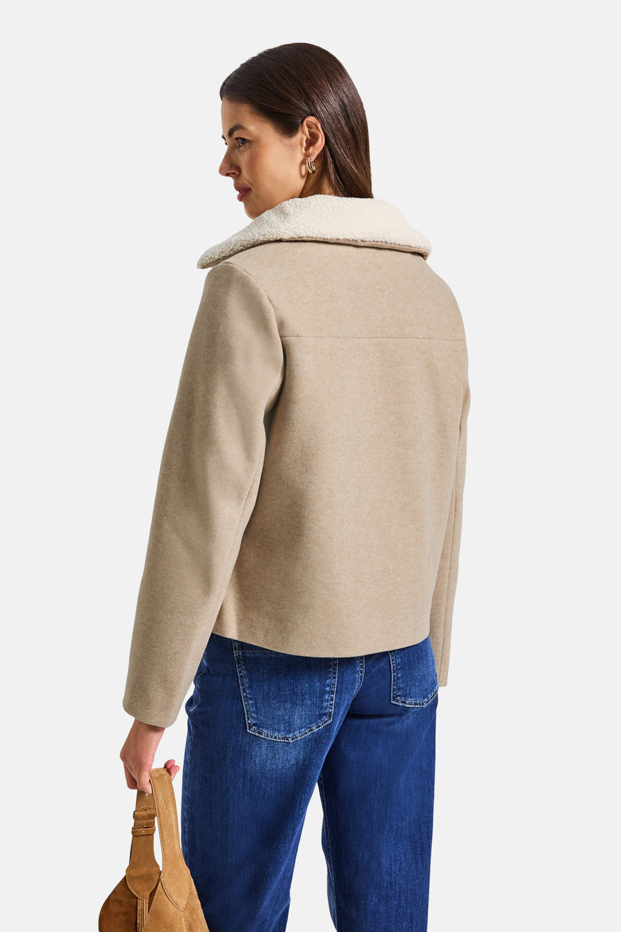 Veste courte beige de Street One avec col en fausse fourrure, portée avec un jean bleu et un sac.