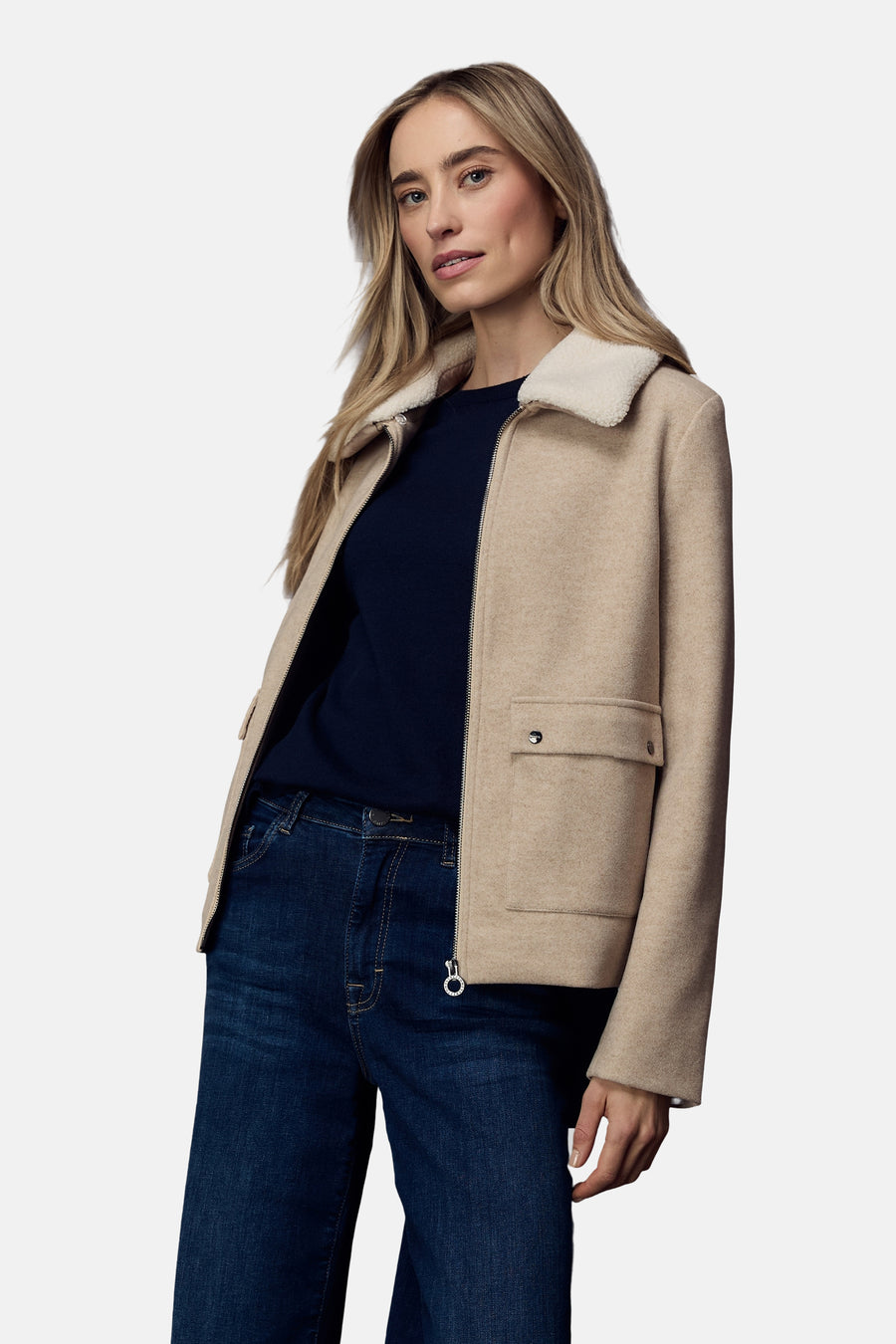 Veste courte beige de Street One, avec col en fausse fourrure, portée avec un pull bleu marine et un jean.
