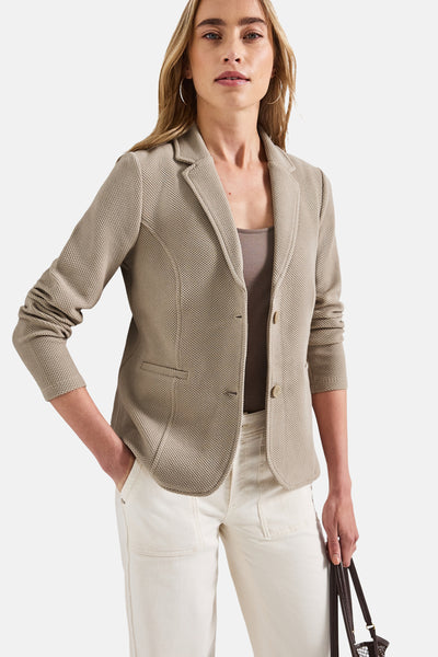 Blazer beige de Street One, avec une texture à motifs, porté avec un top et un pantalon blancs.
