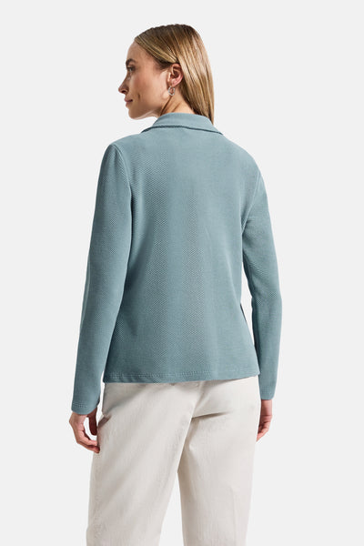 Blazer bleu à manches longues de Street One, avec une texture piquée et porté avec un pantalon beige.