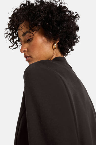 Bruine blazer van Street One, met gouden oorbellen.