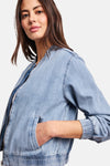 Kort lichtblauw spijkerjack van STREET ONE, bombermodel met ronde hals en ritssluiting, gedragen met een wit T-shirt, een roze broek en metallic sneakers.