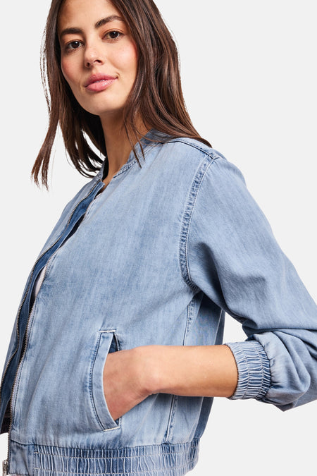 Kort lichtblauw spijkerjack van STREET ONE, bombermodel met ronde hals en ritssluiting, gedragen met een wit T-shirt, een roze broek en metallic sneakers.