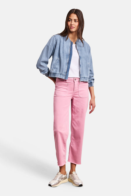Veste courte en jean bleu clair de STREET ONE, coupe bomber à col rond et fermeture éclair, portée avec un t-shirt blanc, un pantalon rose et des baskets métallisées.