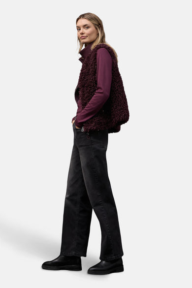 Gilet bordeaux en fourrure synthétique de Street One, porté sur un pull à col roulé et un jean noir.